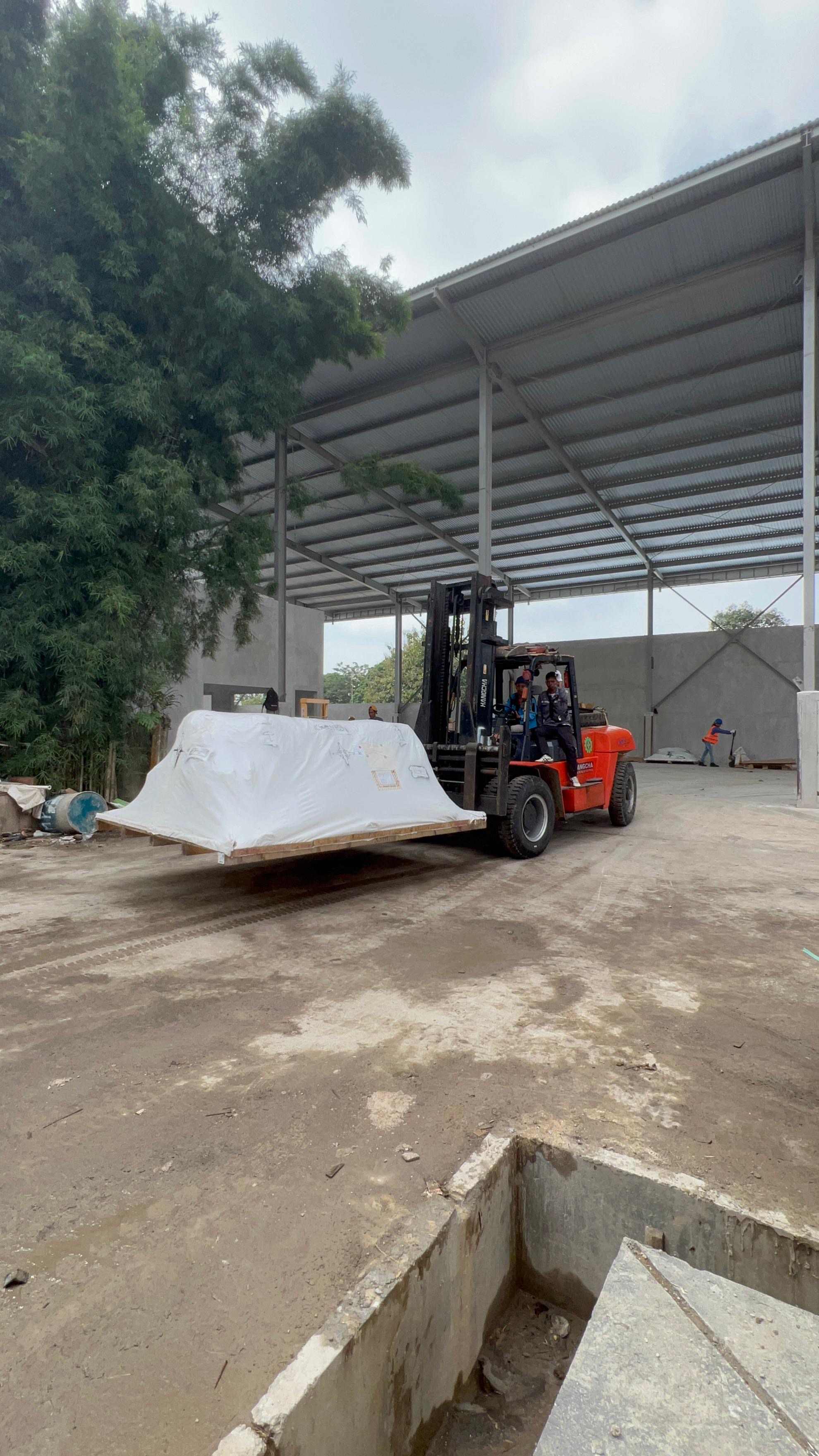 Forklift 10 ton bongkar mesin di pabrik